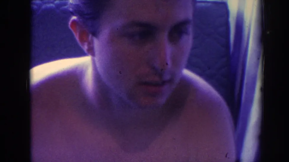 A shirtless man appears close to camera in the 1966 Temple City home-movie footage, looking intently toward something off-frame.