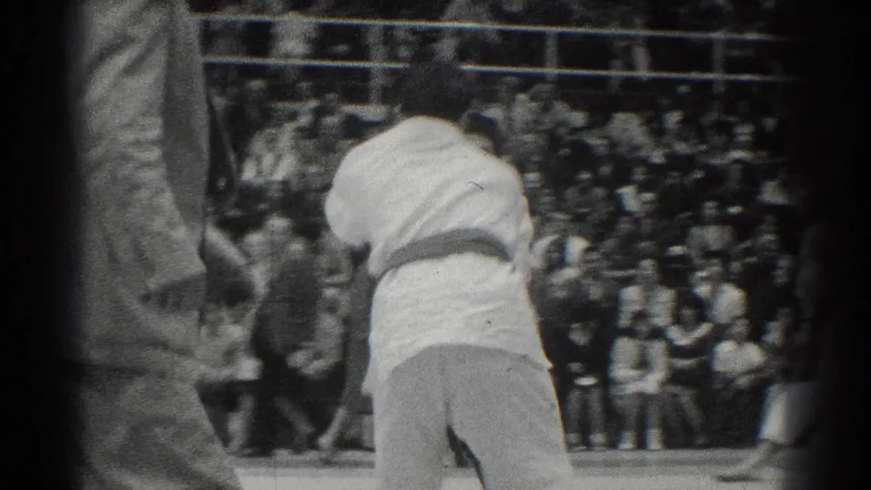 1966 West Covina karate competition footage showing two competitors in white gi engaged before a crowded set of bleachers.