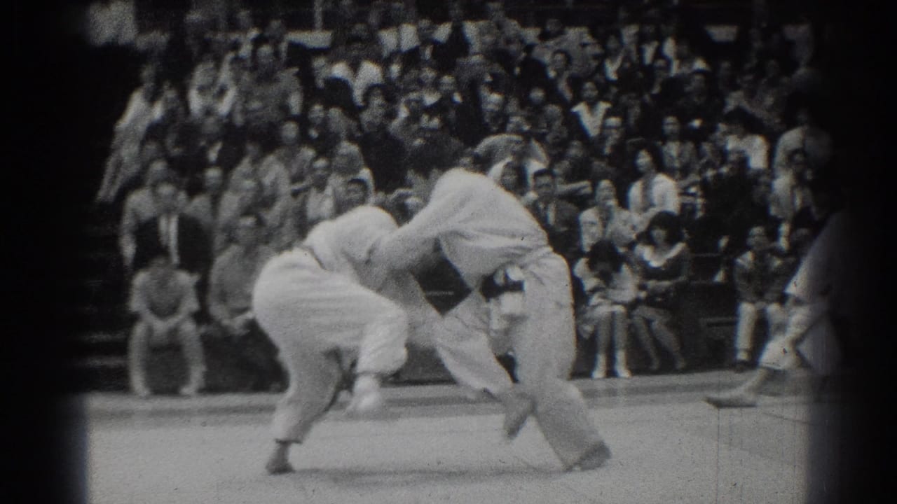 One competitor bends forward as the other grips him during a throw attempt.