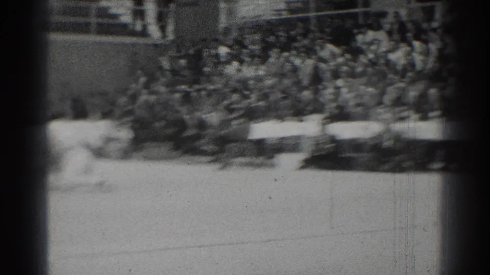The 1966 indoor gym scene shows spectators in bleachers and officials' tables while the match action falls mostly outside the frame.
