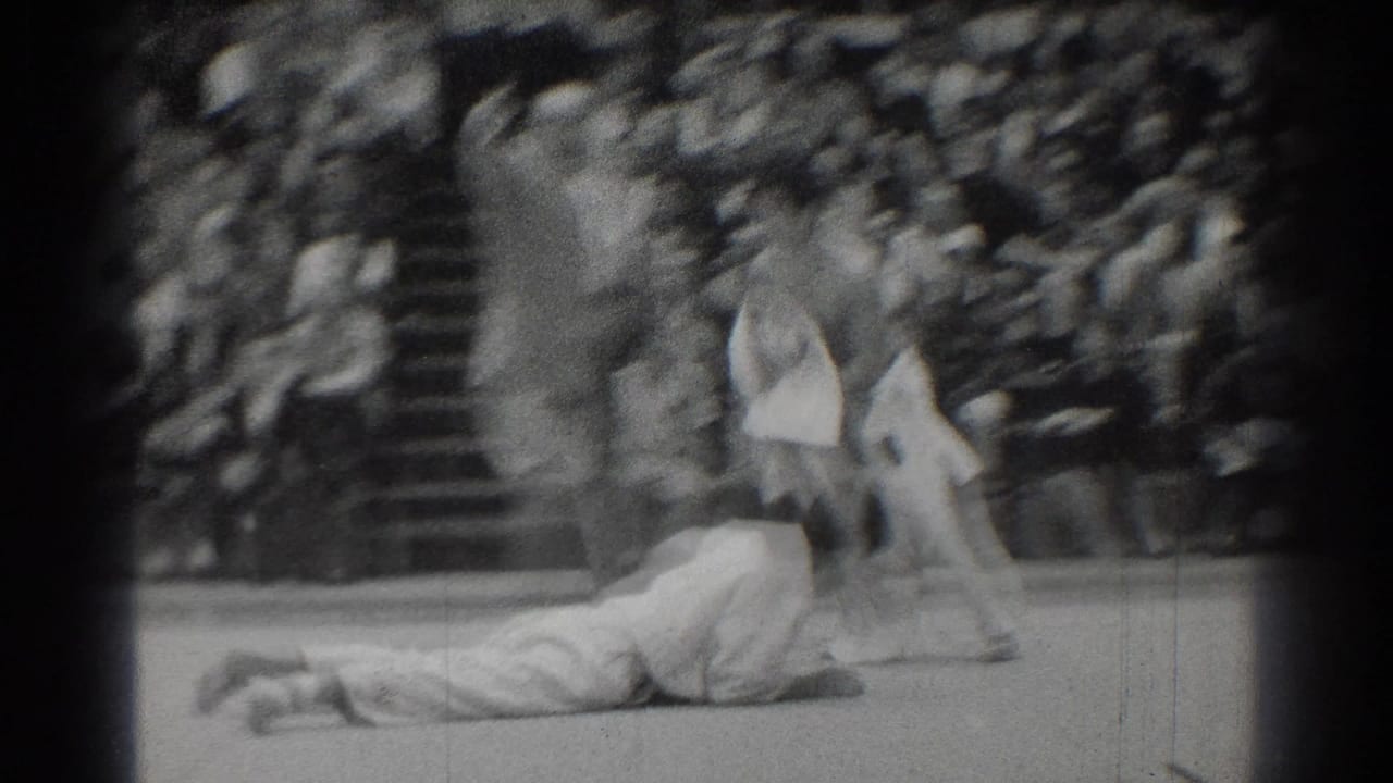 A judo competitor is thrown to the mat while the other stands nearby.
