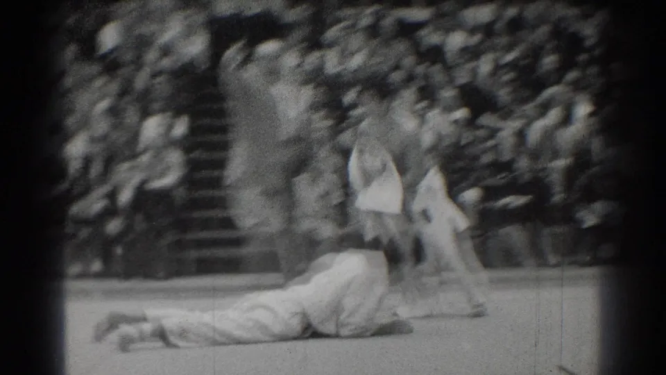 During the West Covina judo match, one athlete lies on the mat after a throw as the other remains upright near the crowd.