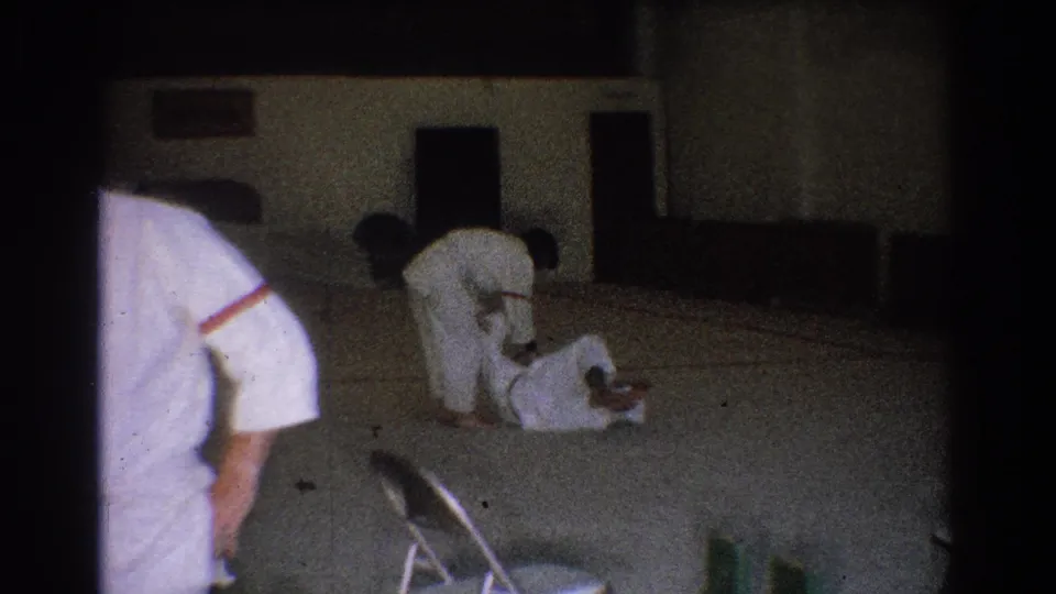 A 1966 West Covina judo training moment shows one practitioner down on the mat as another bends over during a takedown or hold.
