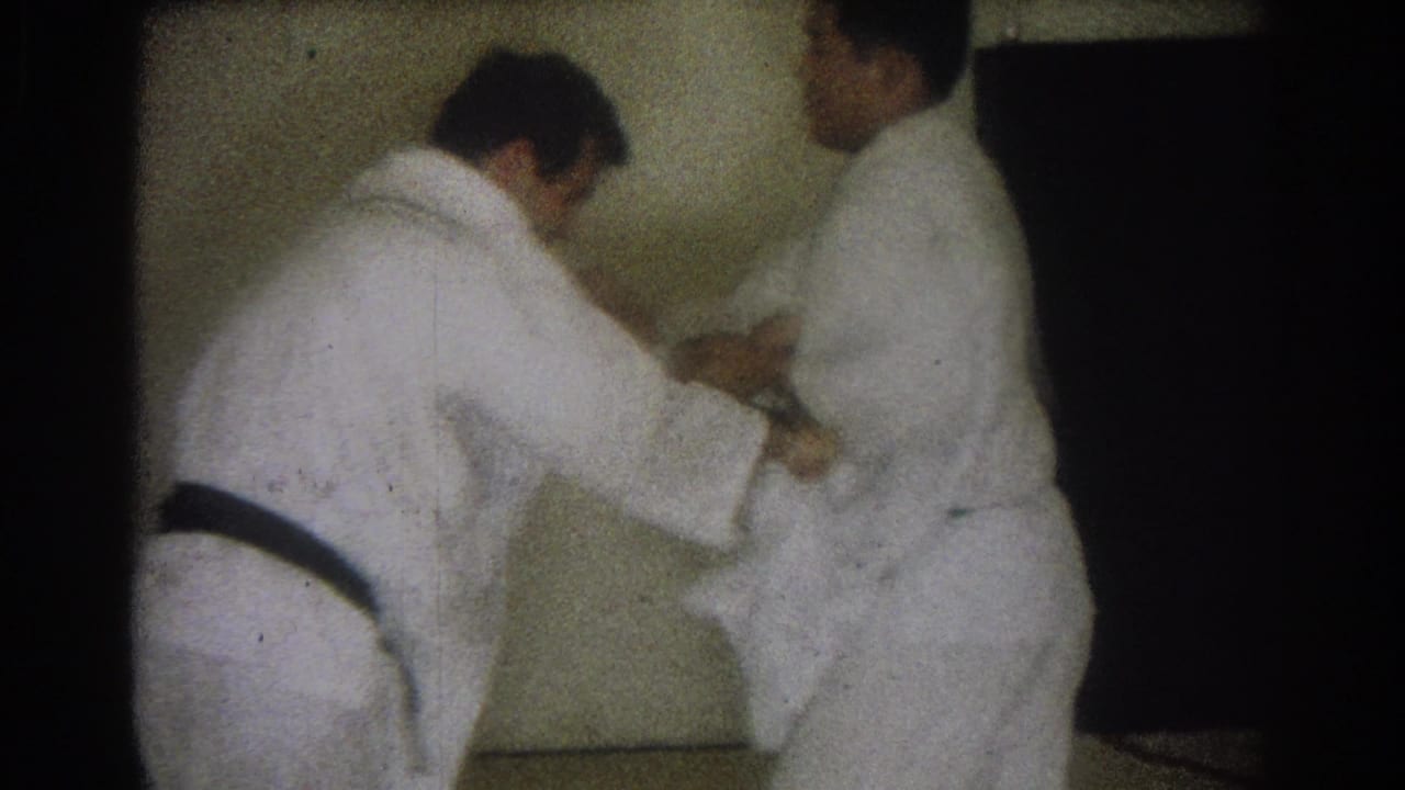 In the 1966 West Covina footage, one adult man bends at the waist as another holds position during judo practice.