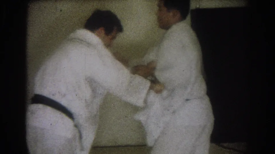 In the 1966 West Covina footage, one adult man bends at the waist as another holds position during judo practice.