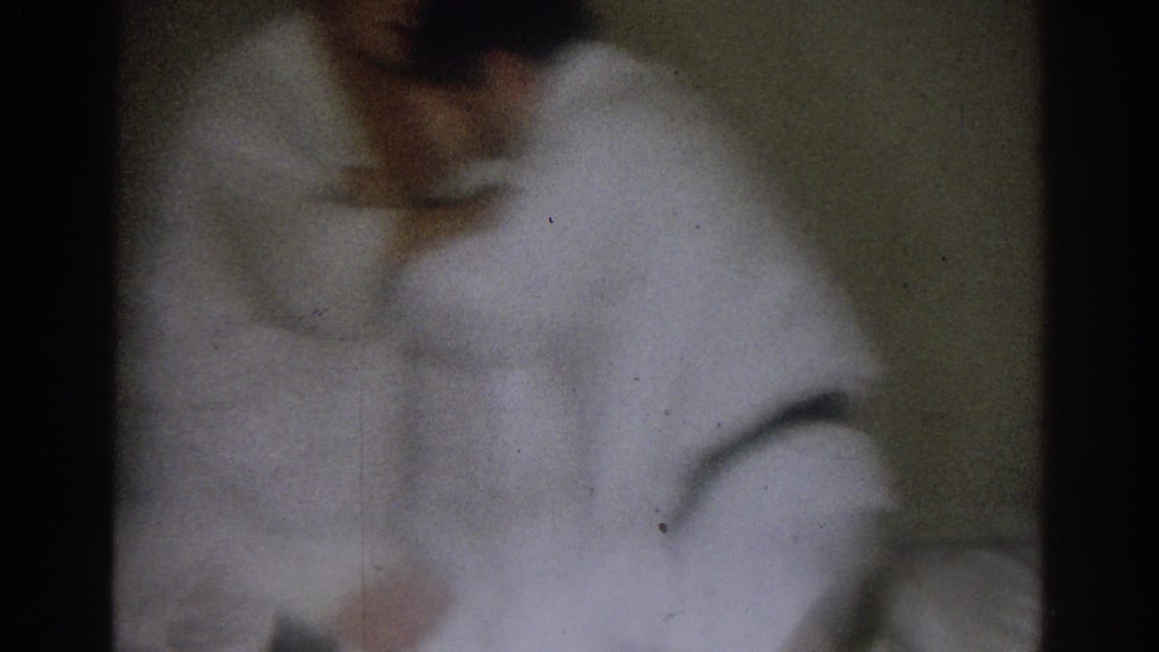 A white-uniformed competitor bends forward during the indoor martial arts exchange, with another figure partly visible nearby.