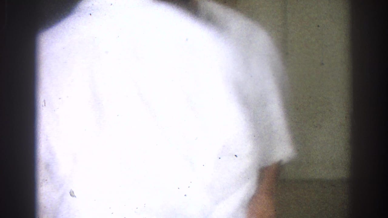 Close, soft 8mm view of a white gi from behind during the West Covina martial arts session, with another participant partly visible.