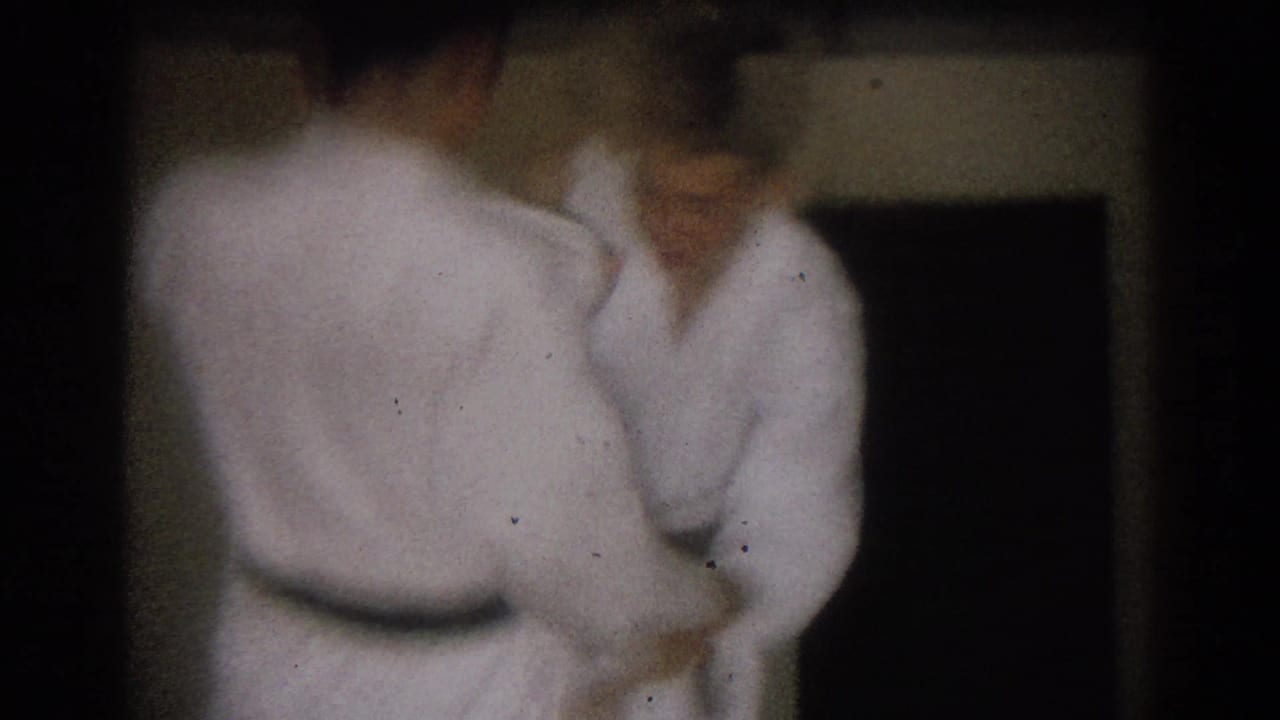Two men in white karate uniforms face each other in a dim interior during a short 1966 West Covina practice sequence.