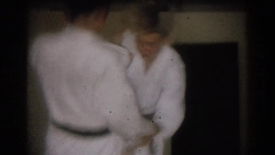 Two men in white karate uniforms face each other in a dim interior during a short 1966 West Covina practice sequence.