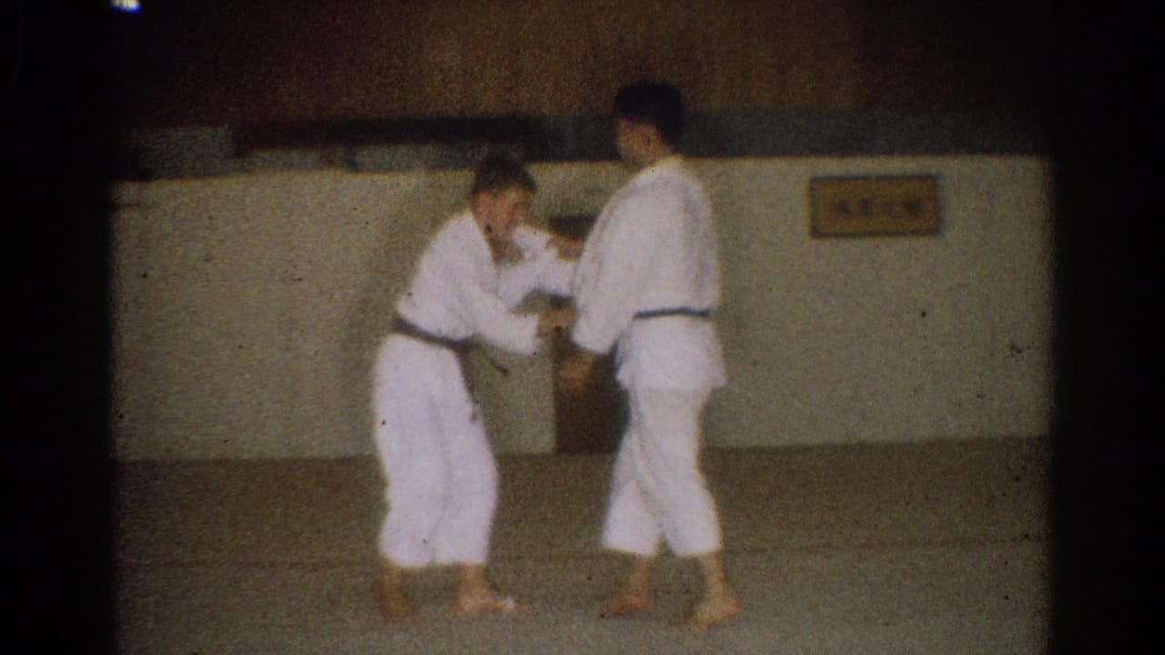 Two young men in white gi and dark belts practice hand grips on a mat in a West Covina dojo setting.