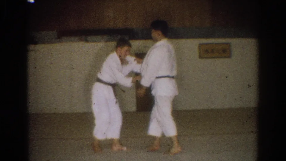 Two young men in white gi and dark belts practice hand grips on a mat in a West Covina dojo setting.