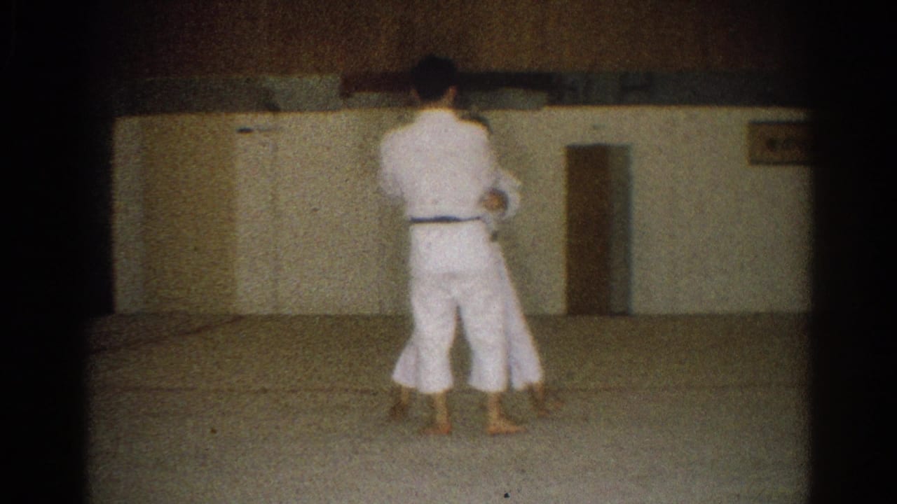 In the 1966 West Covina dojo footage, one man in a white gi faces away while another is partly visible during practice.
