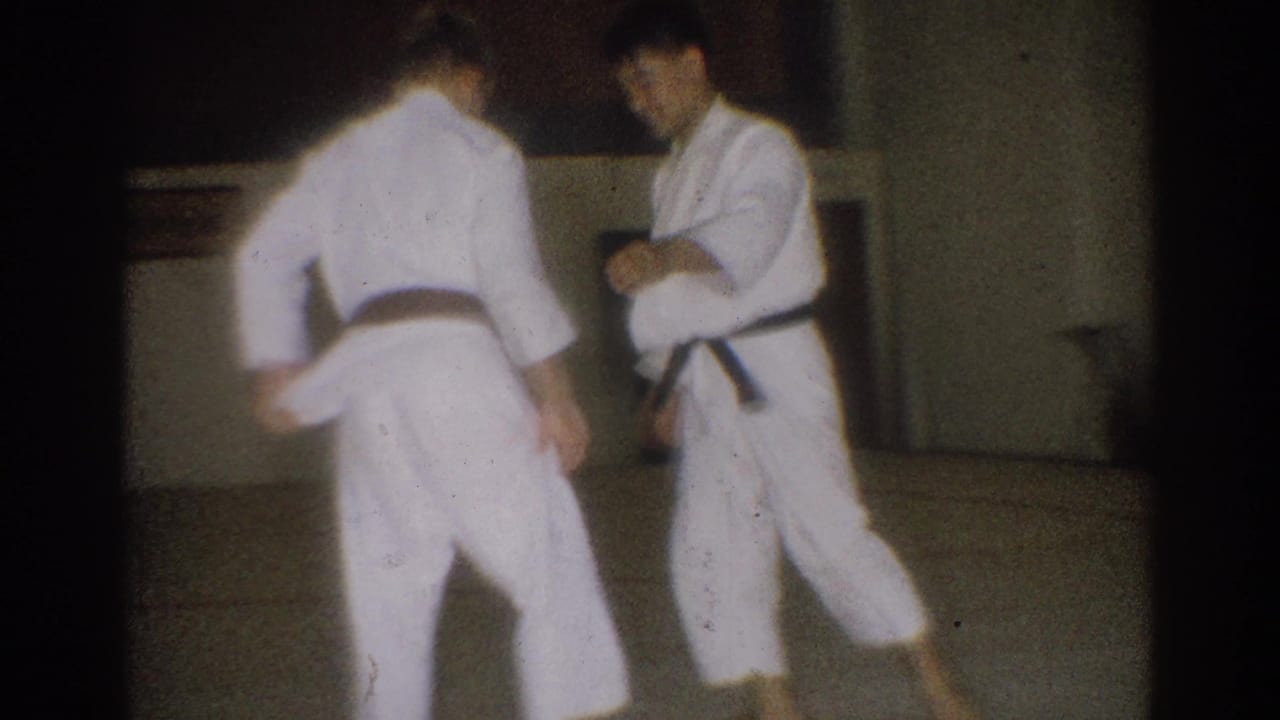 Two adult men in white gi and black belts face each other after a technique in the metadata-supported West Covina indoor practice space.