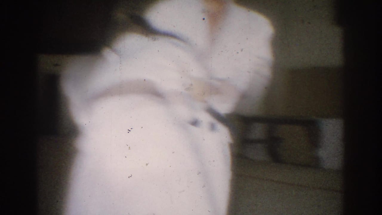 A close handheld 8mm view shows the two judo practitioners partially cropped as they move through a technique in the dojo.
