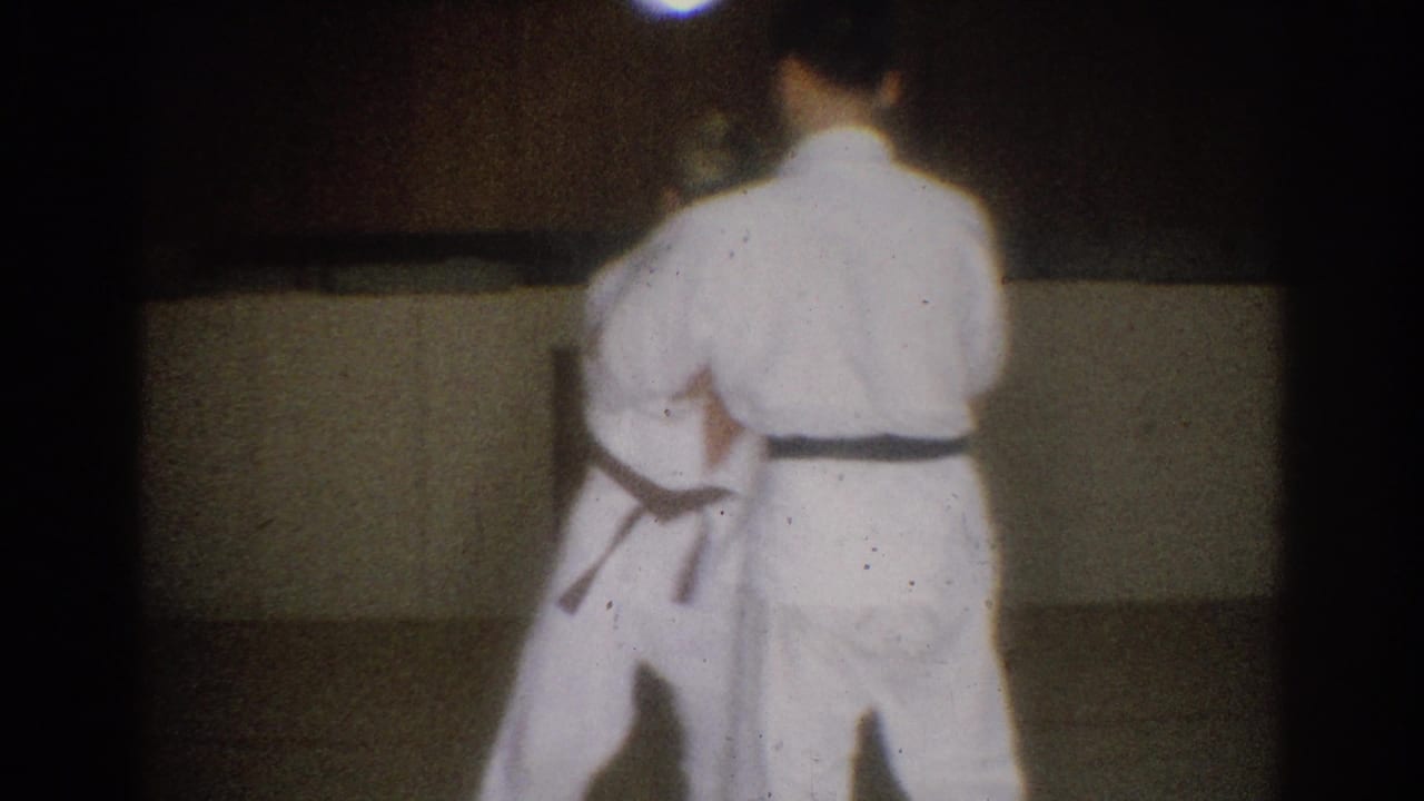 Two students in white gi and dark belts appear to practice a martial arts technique in the 1966 West Covina home-movie footage.