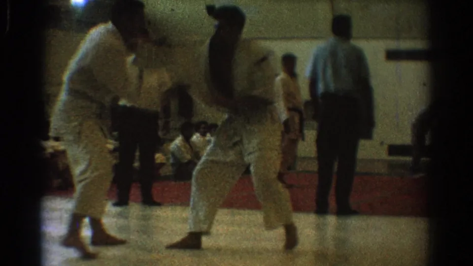A close exchange between two uniformed martial artists is captured in soft 8mm focus inside the West Covina gymnasium.