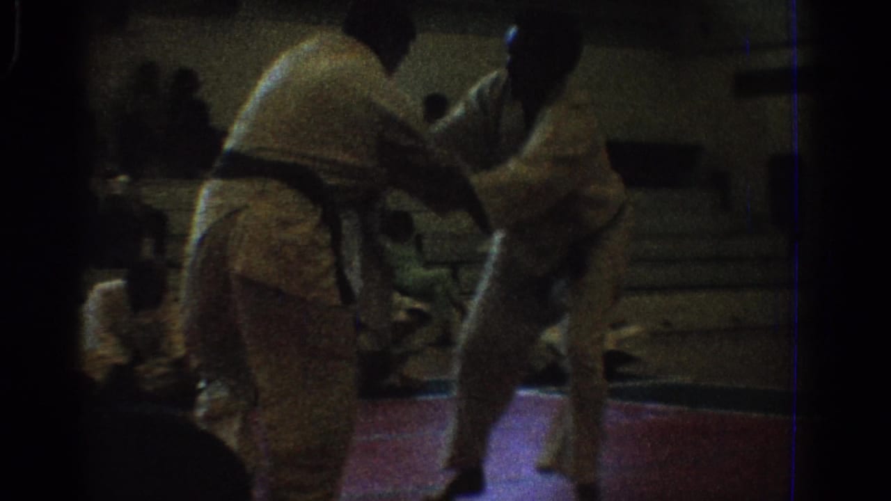 West Covina 1966 home-movie frame of two martial artists separating or repositioning during a gymnasium match.