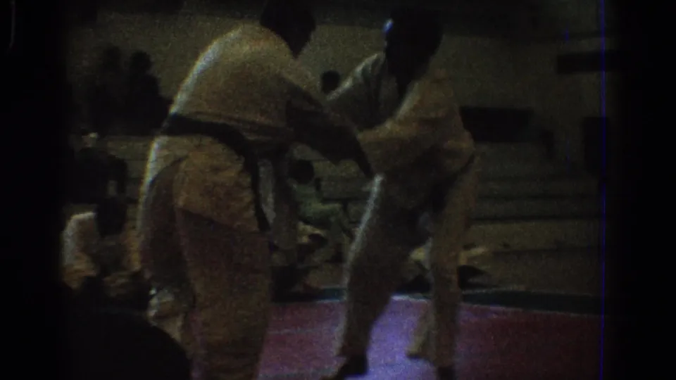 West Covina 1966 home-movie frame of two martial artists separating or repositioning during a gymnasium match.