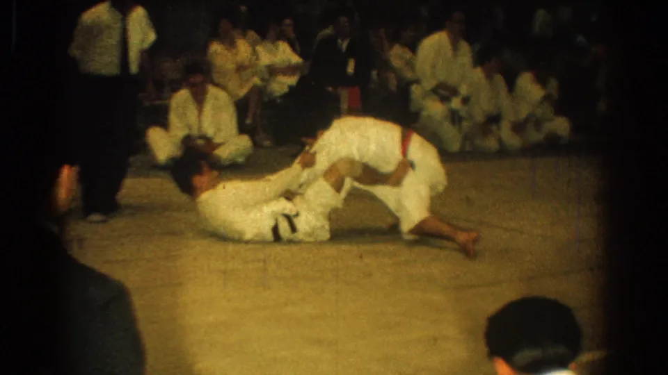 A martial arts participant in a white gi leans over an opponent on the mat during the 1966 West Covina match.
