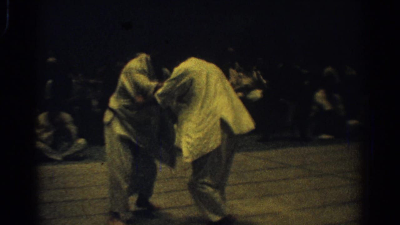 Two judo competitors in white gi lean into a standing grip during the West Covina championship footage.