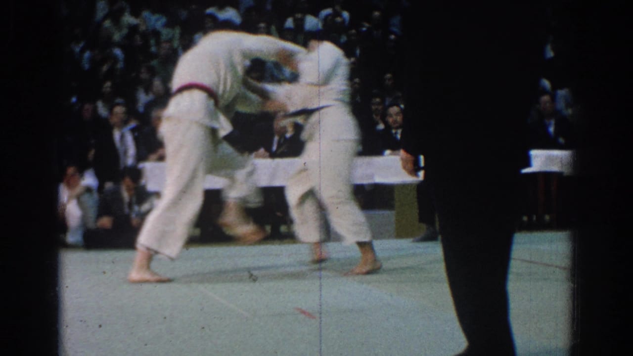 Two martial arts competitors clinch during a 1966 West Covina match, with an official partly blocking the spectator-shot view.