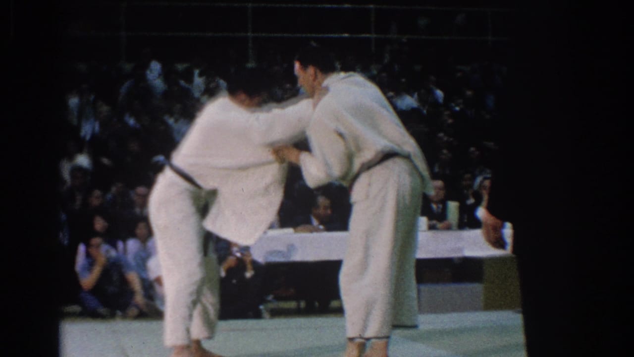 A close exchange in the 1966 West Covina karate footage shows both competitors bent forward on the mat before the audience.