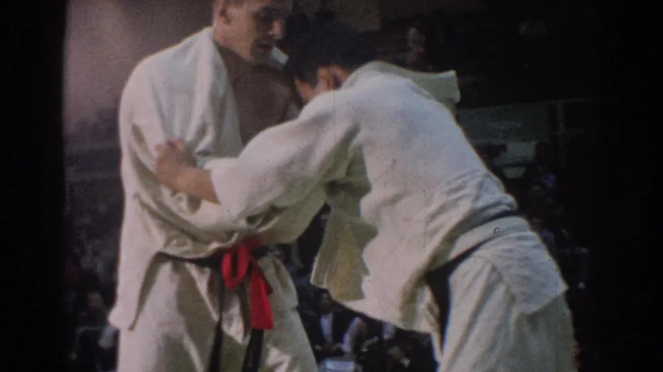 Near the end of the clip, the two adult judokas maintain close grips on the mat during the 1966 West Covina indoor competition.