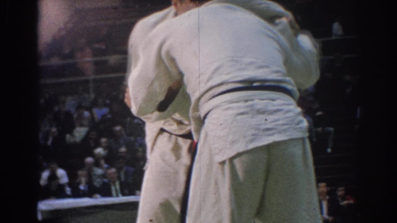 One martial arts competitor is seen from behind while grappling with another athlete in a 1966 indoor West Covina match.