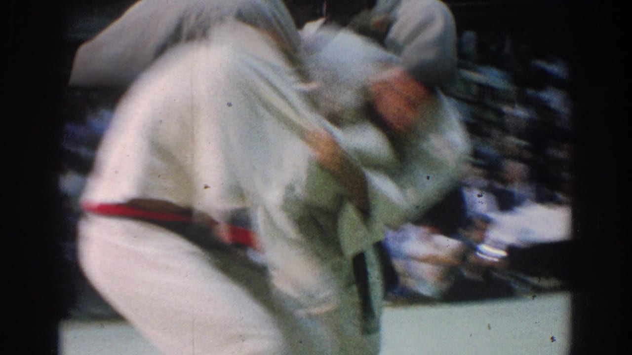 Blurred close view of two judo competitors in white gis grappling on a mat.