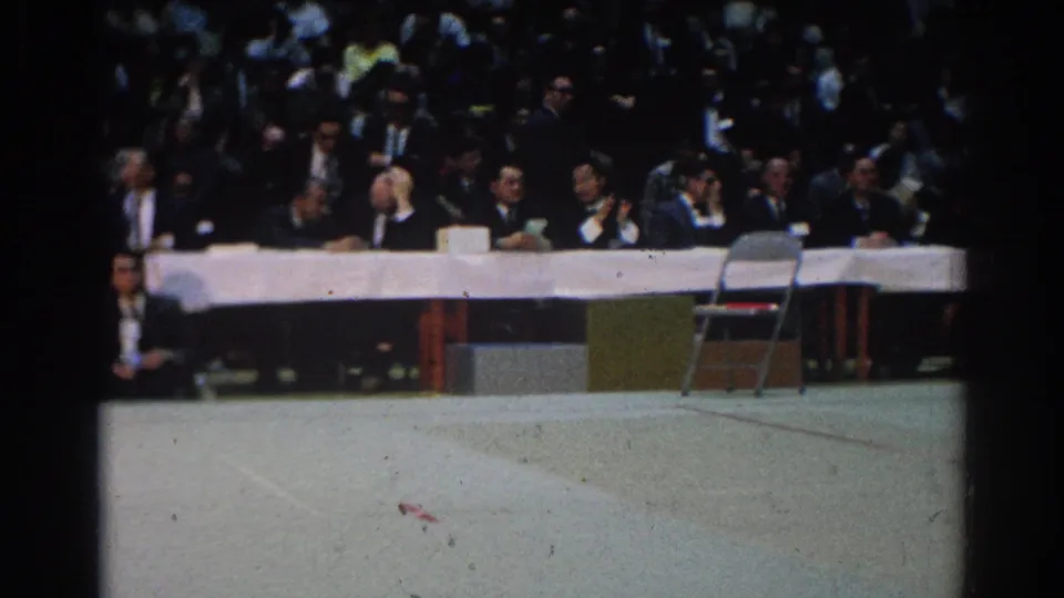 A folding chair and long officials table occupy the foreground while spectators watch from behind at the 1966 West Covina event.