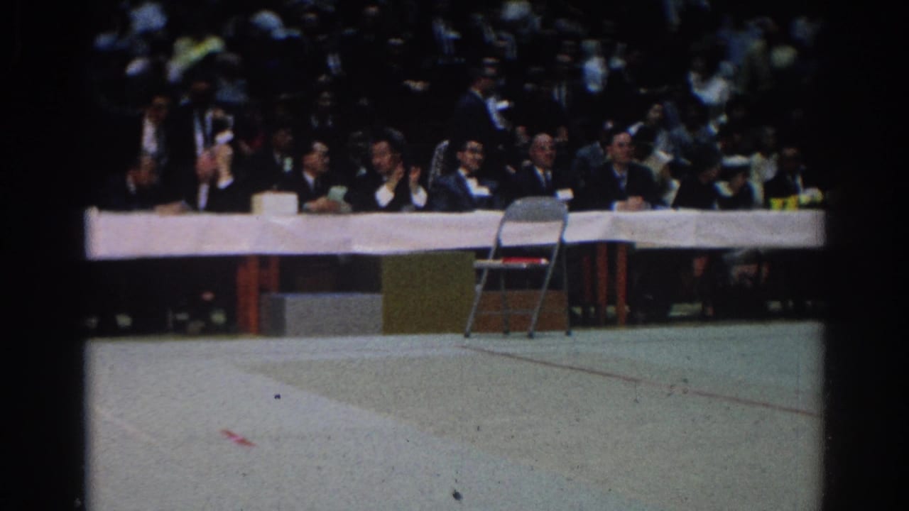 In West Covina in 1966, suited officials sit at a long white table during an indoor karate or sports event.