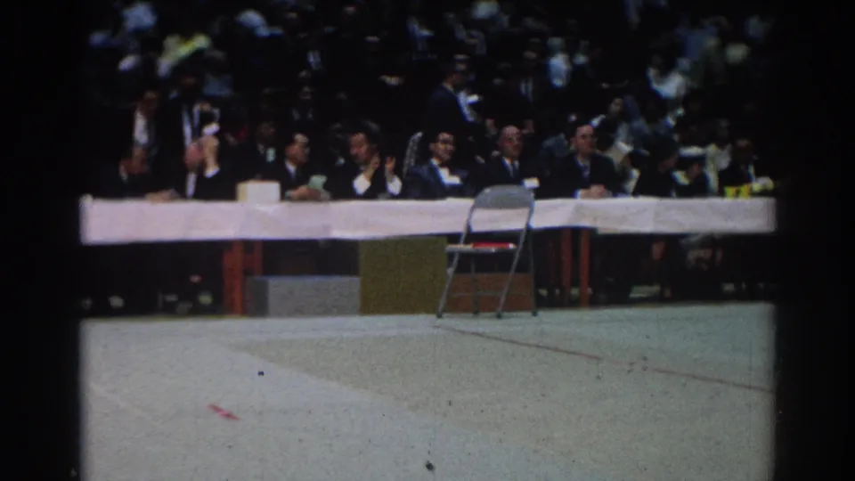 In West Covina in 1966, suited officials sit at a long white table during an indoor karate or sports event.