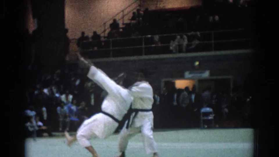 One competitor appears airborne during a martial arts throw in the 1966 West Covina competition footage.