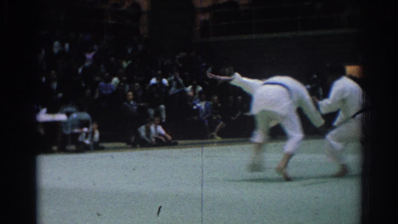 A judo throw is underway as one man bends forward and the other lifts off the mat in the West Covina demonstration.
