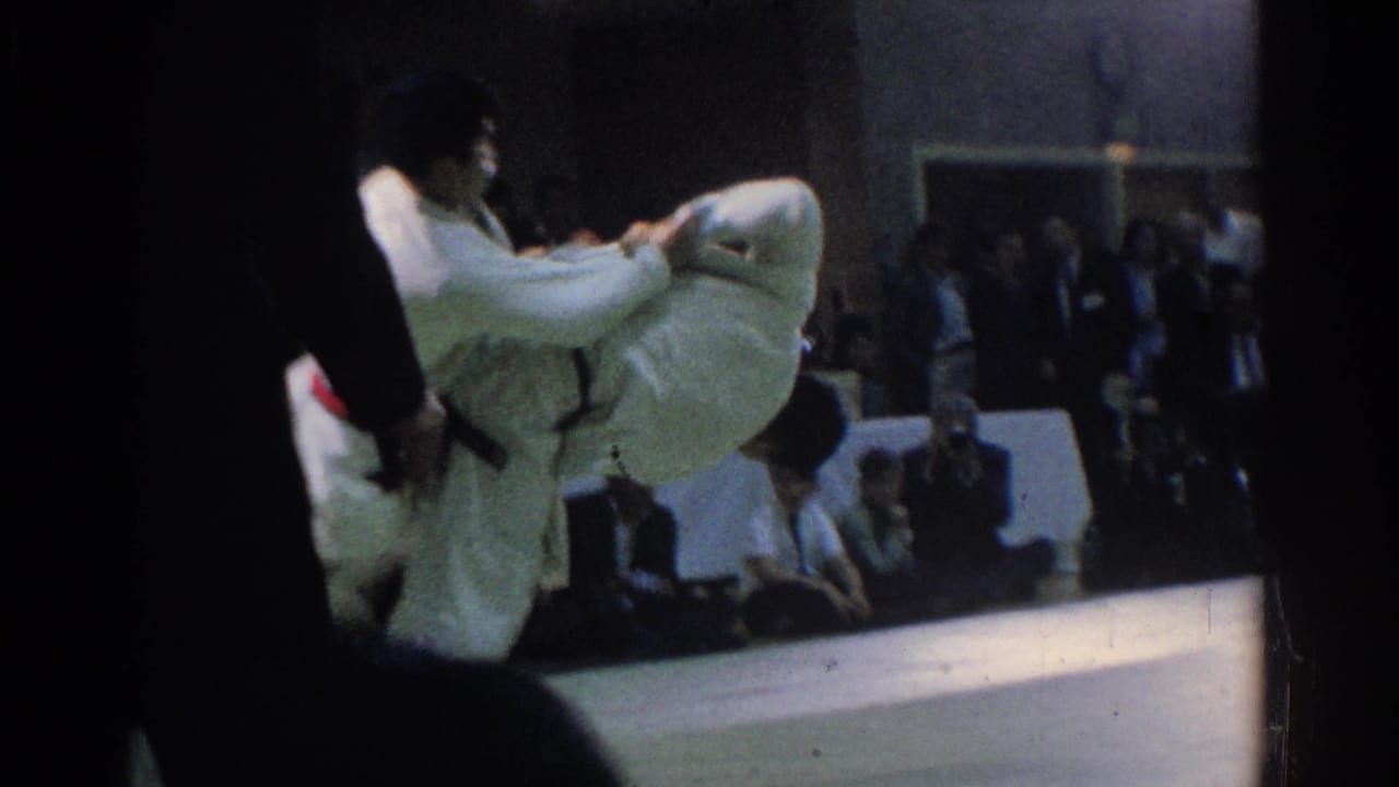 Two judo competitors in white uniforms grapple on a mat as one begins a throw.