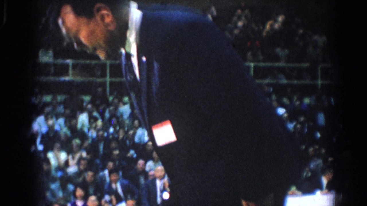 Referee bends forward near a crowded gymnasium audience.