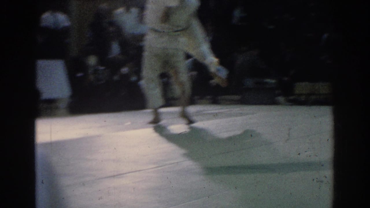 The 1966 West Covina judo match continues with one competitor lifted or turning as motion blur emphasizes the throw.