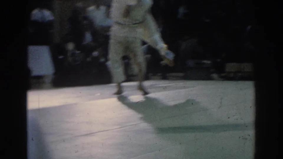 The 1966 West Covina judo match continues with one competitor lifted or turning as motion blur emphasizes the throw.