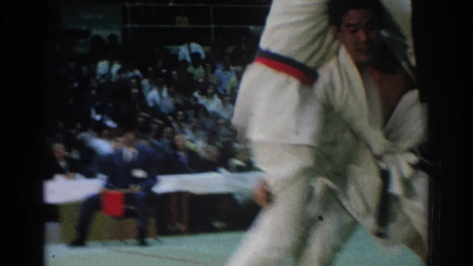 A closer 1966 West Covina frame shows the judo competitors' gi and belt detail, with spectators blurred in the background.