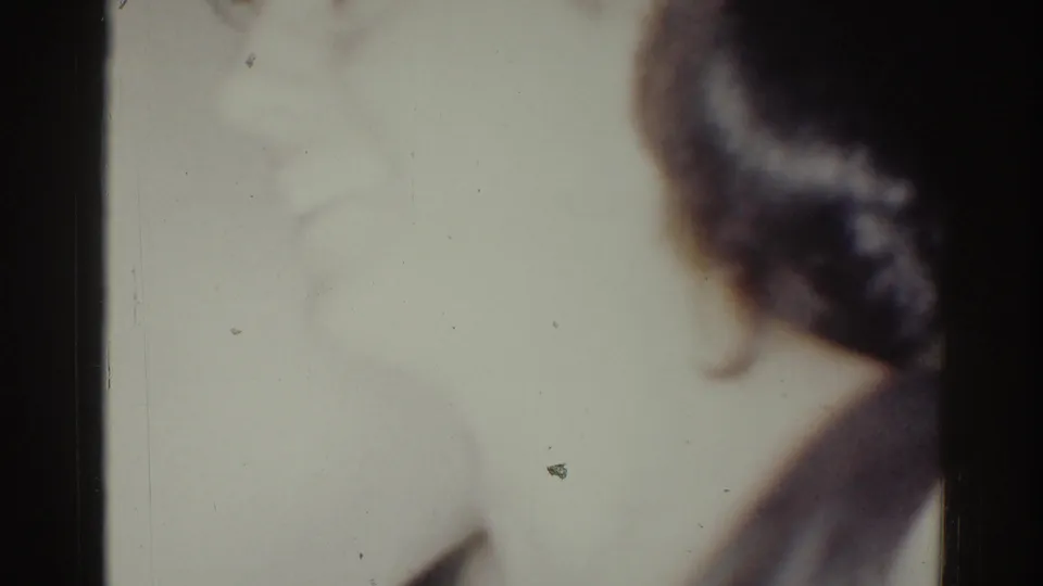 A blurred figure appears near a pale interior wall in this 1967 Los Angeles 8mm home-movie frame.