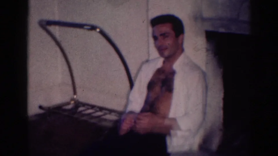 A man in an open white shirt sits near a fireplace and curved household fixture in a 1967 Los Angeles home interior.