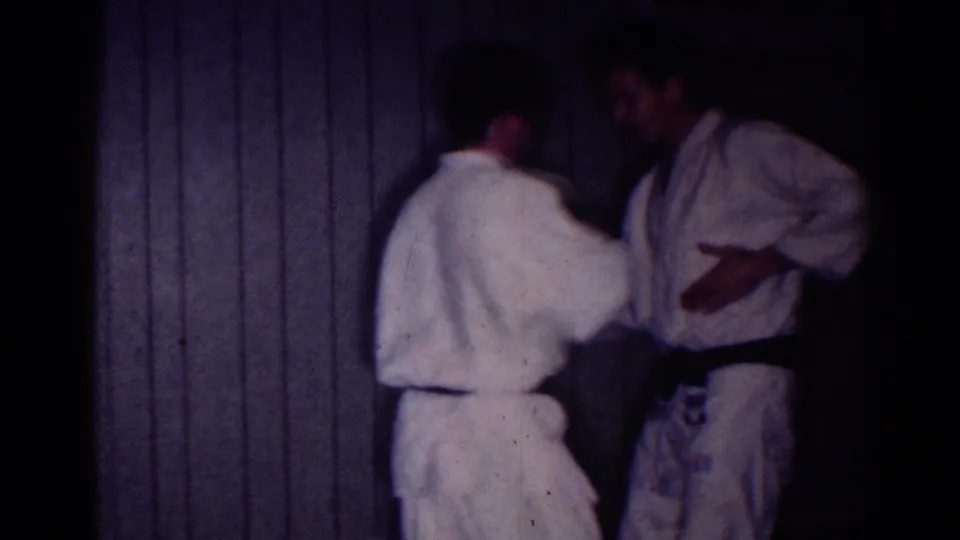 In the 1967 Los Angeles footage, one man in a white uniform reaches toward a black-belted partner during indoor practice.