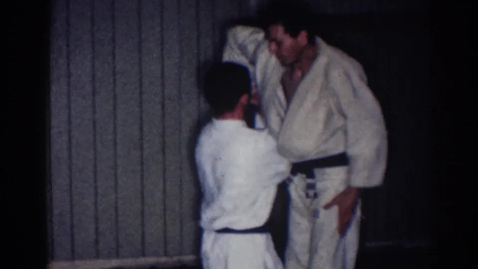 1967 Los Angeles frame of two judo athletes in close contact, with one reaching upward toward the other's sleeve or shoulder.