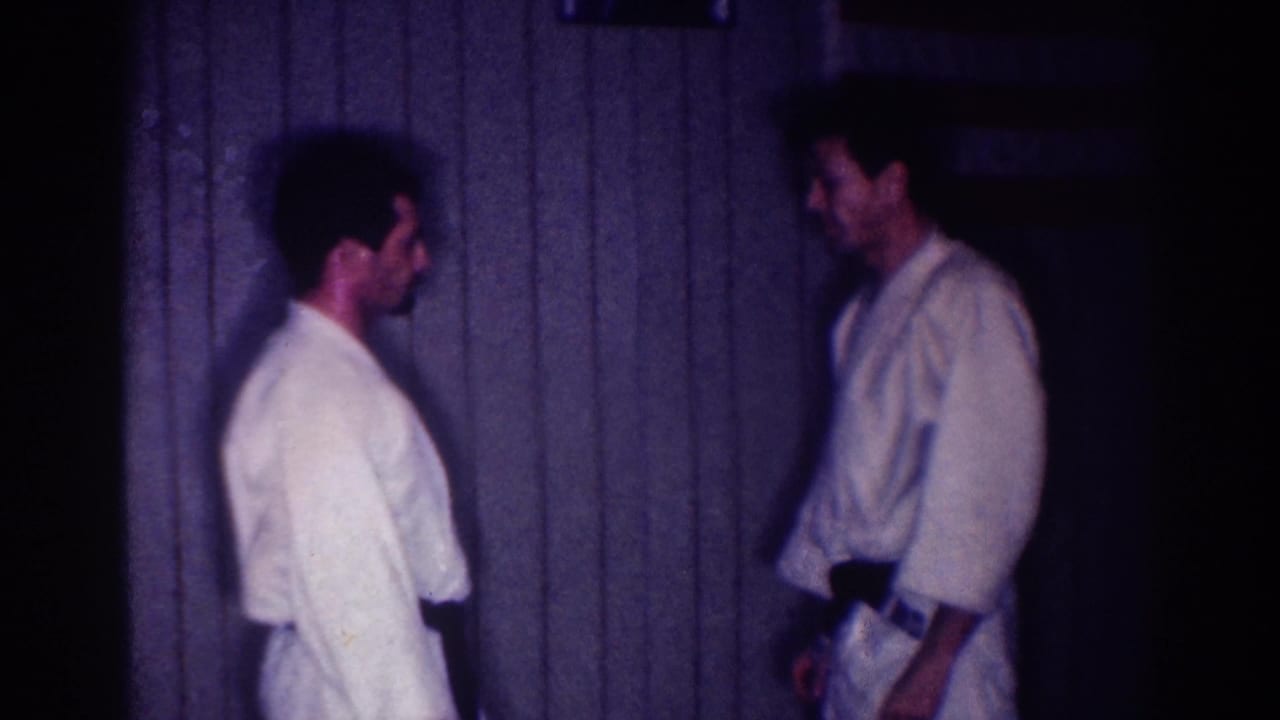 Two adult men in white gi and dark belts face off in a dim interior identified by metadata as Los Angeles in 1967.