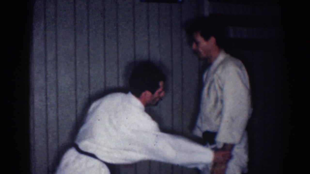 A practitioner extends both arms toward his partner's lower arm or belt area during an indoor karate drill in 1967 Los Angeles footage.