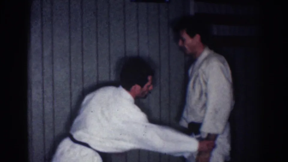 A practitioner extends both arms toward his partner's lower arm or belt area during an indoor karate drill in 1967 Los Angeles footage.
