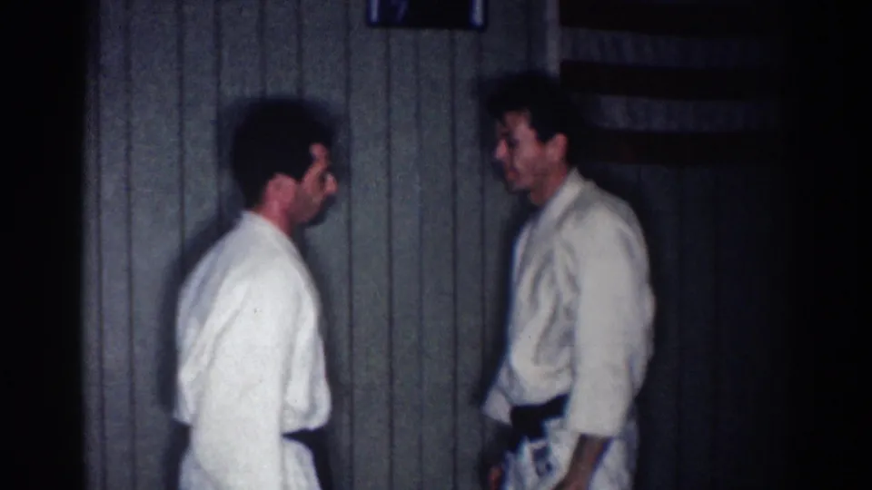 In the final frame, two adult judo practitioners stand facing each other indoors against the dark paneled background.