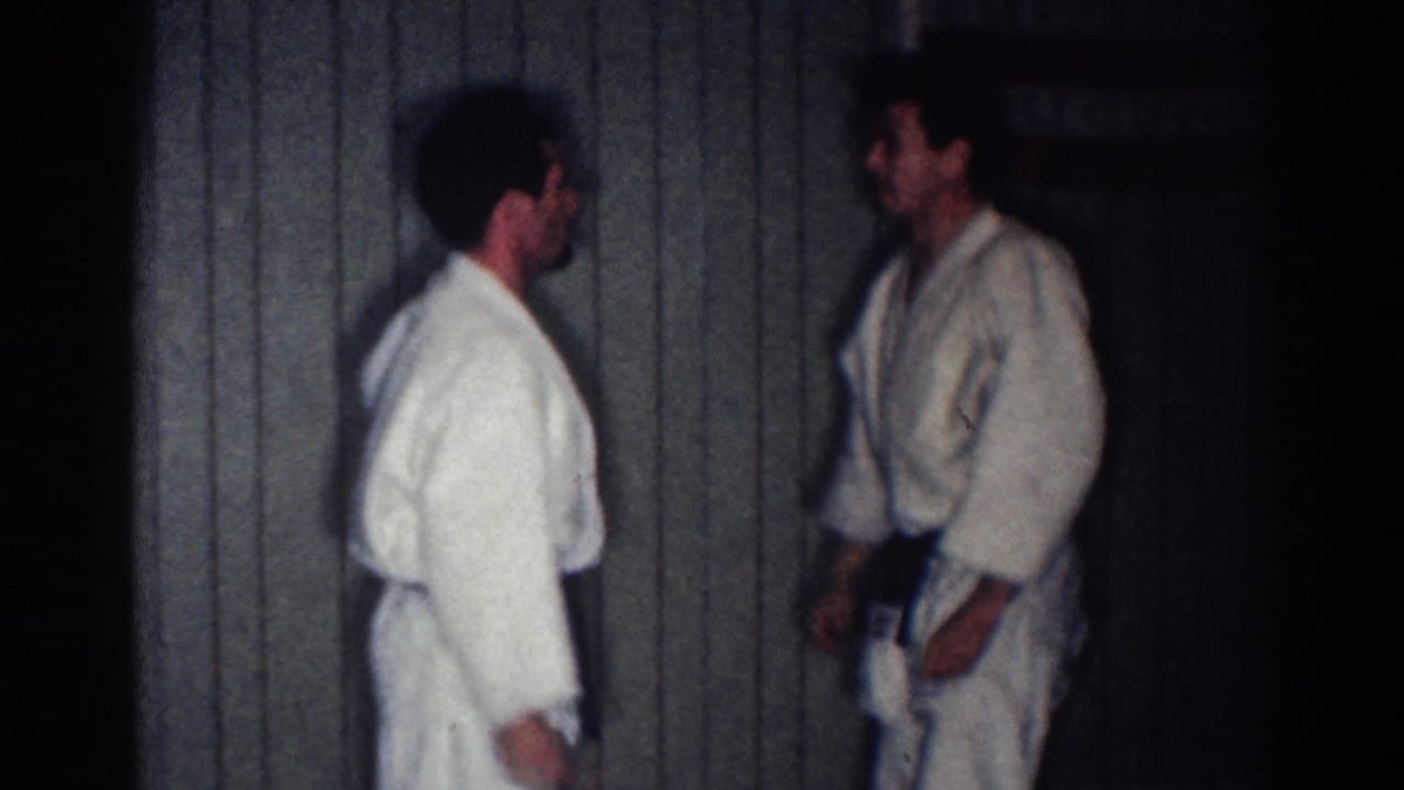 Two karate students in gi stand facing each other in an indoor practice space.