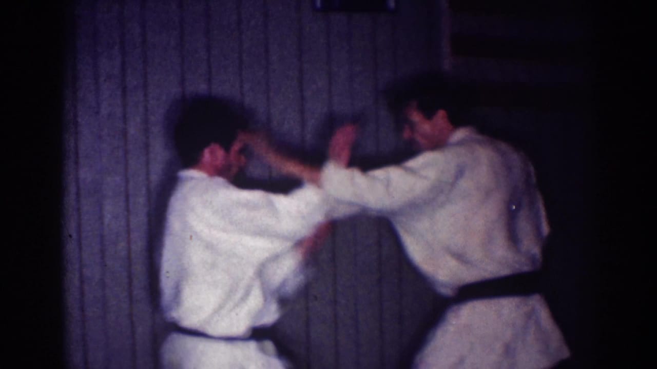 Two judo practitioners face each other with arms extended in a defensive drill.