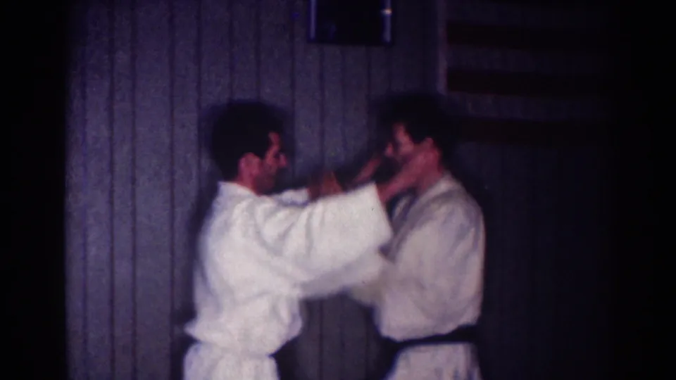 During the 1967 home-movie clip, one man extends both hands toward his partner in a controlled karate demonstration.